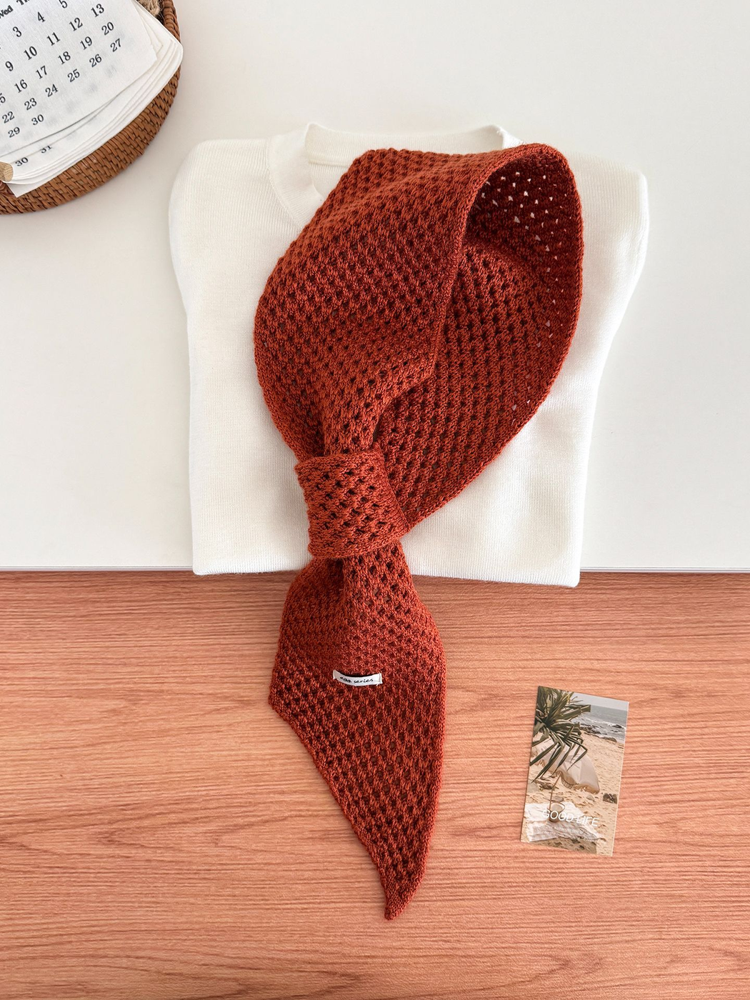 Orange and Brown openwork pull-through scarf displayed with a folded white top
