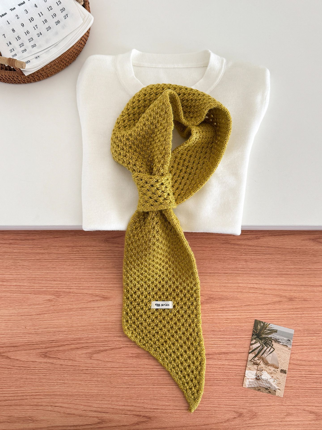 Mustard Yellow openwork pull-through scarf displayed with a folded white top