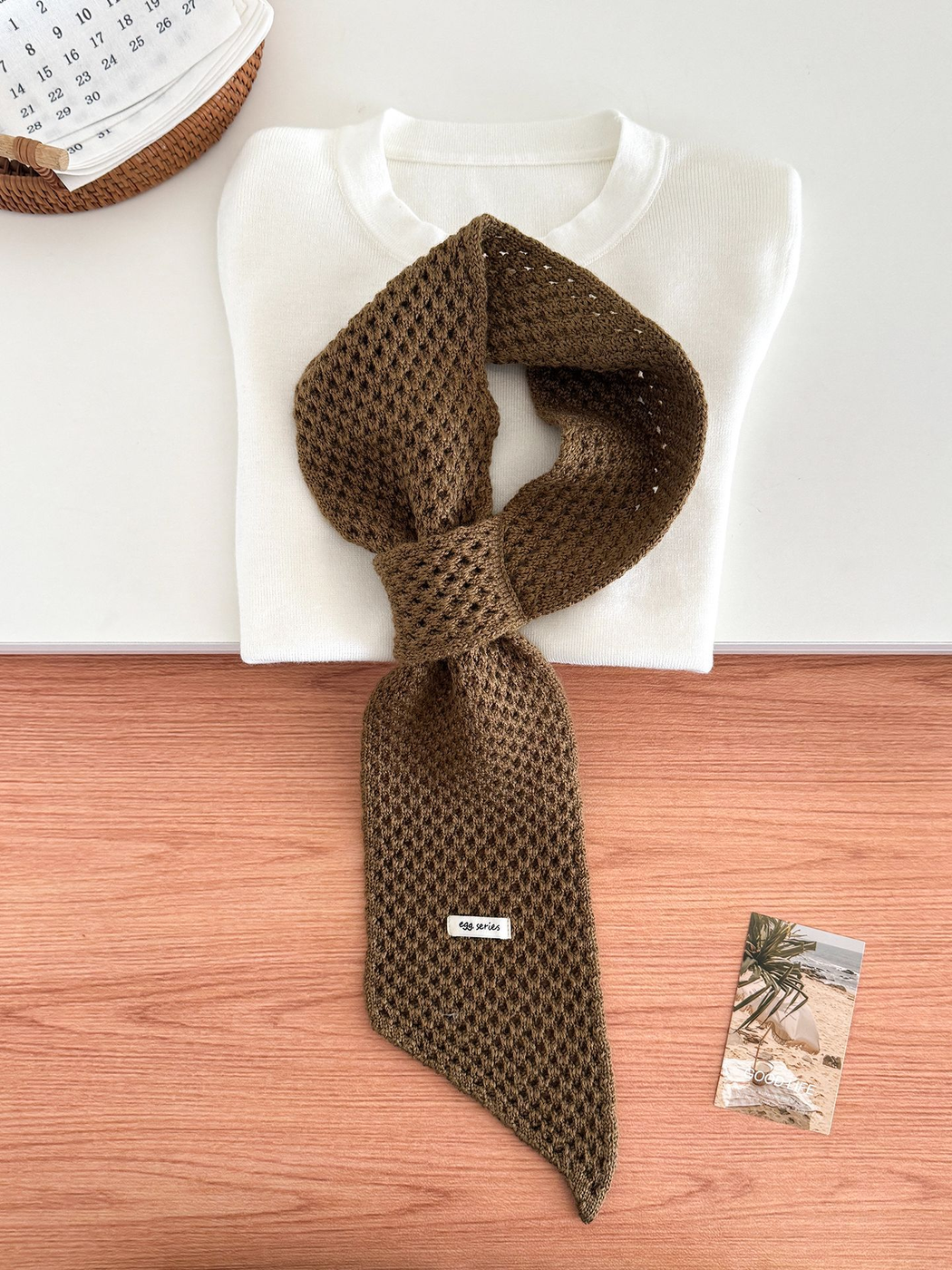 Coffee openwork pull-through scarf displayed with a folded white top