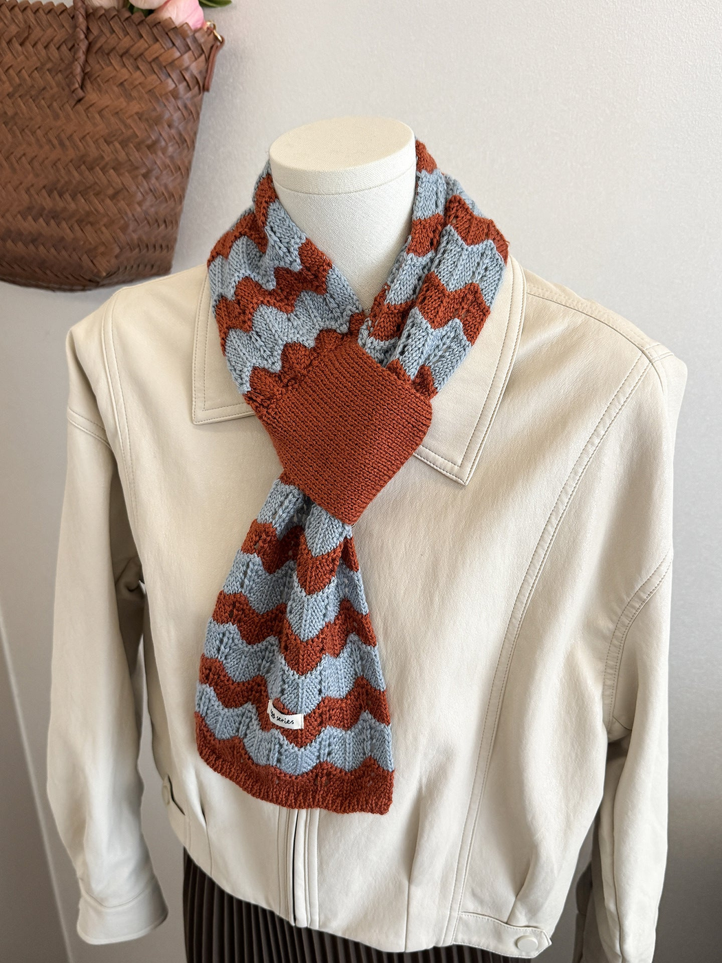Blue and orange wavy knit pull-through scarf styled on a mannequin