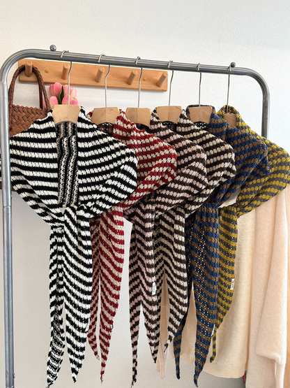 Six striped triangle scarf colorways displayed together on a rack