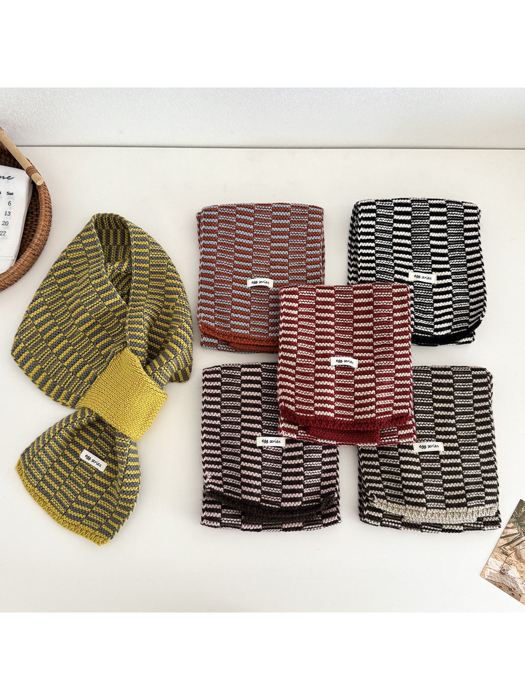 Multiple color variations of the geometric pull-through scarf displayed together