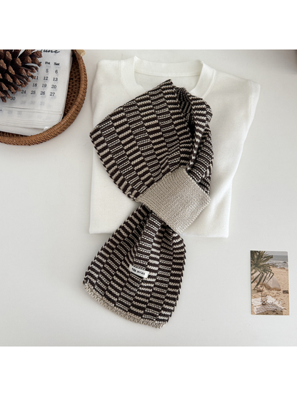 Khaki / Brown geometric pull-through scarf arranged over a folded cream top