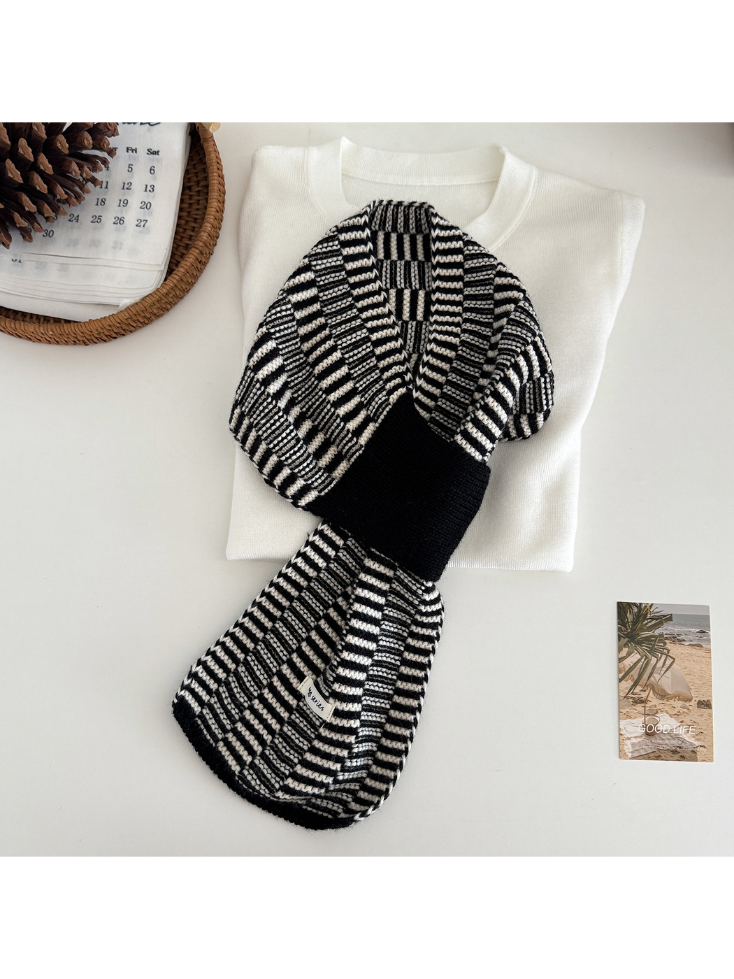 Black / White geometric pull-through scarf arranged over a folded cream top
