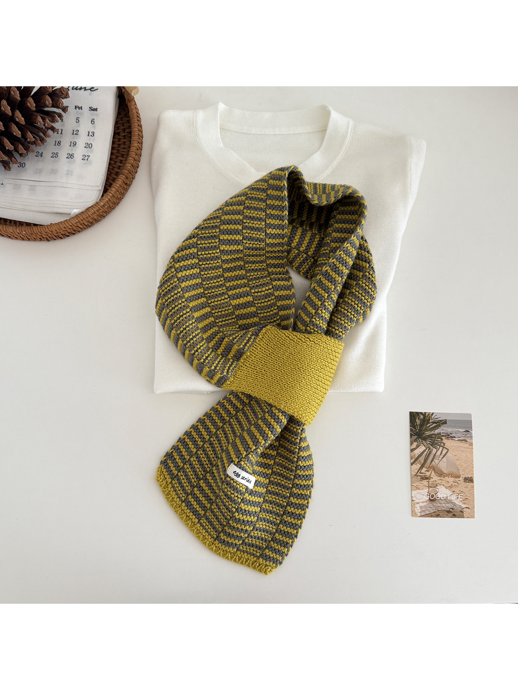 Mustard Yellow geometric pull-through scarf arranged over a folded cream top
