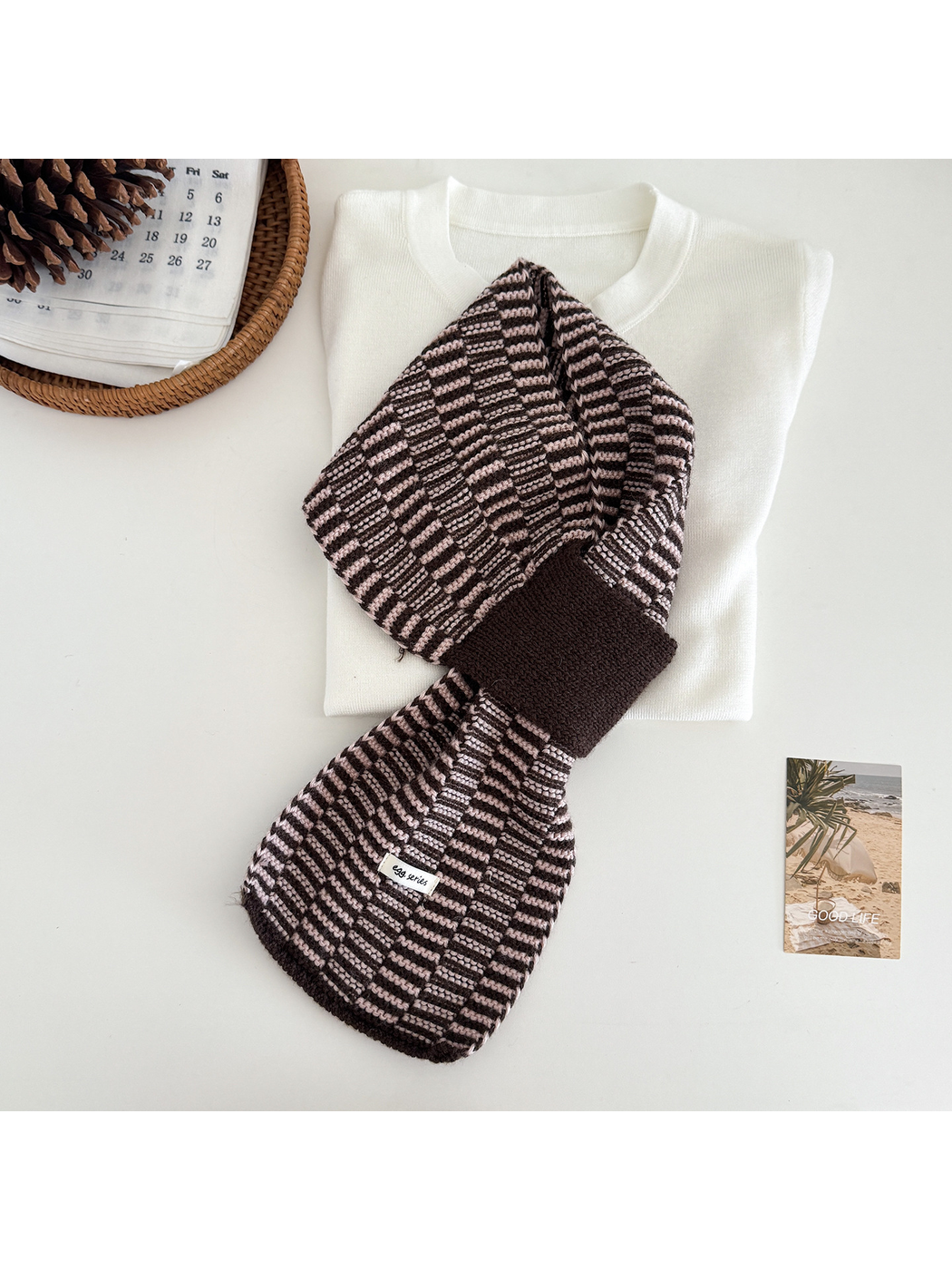 Pink / Brown geometric pull-through scarf arranged over a folded cream top