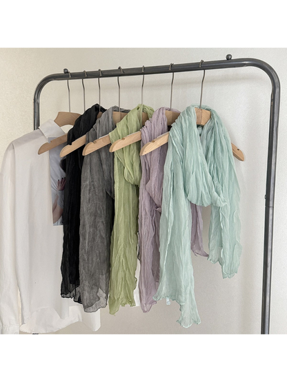 Black, gray, green, light purple and mint crinkled scarves displayed on hangers