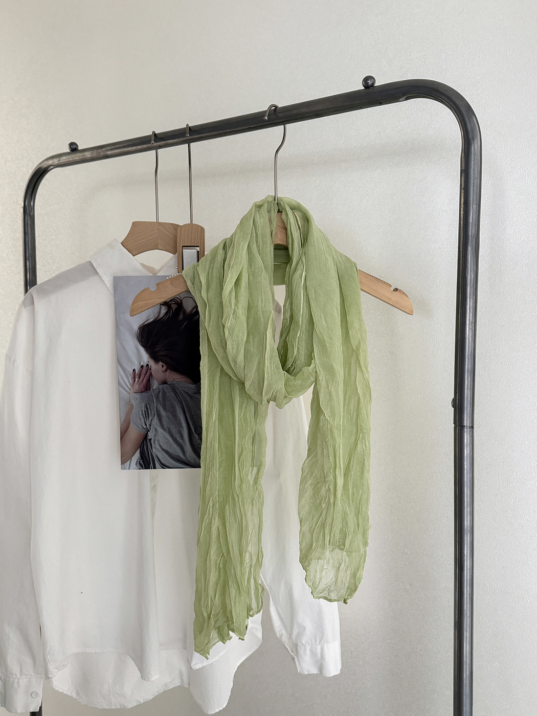 Green crinkled scarf draped on a hanger