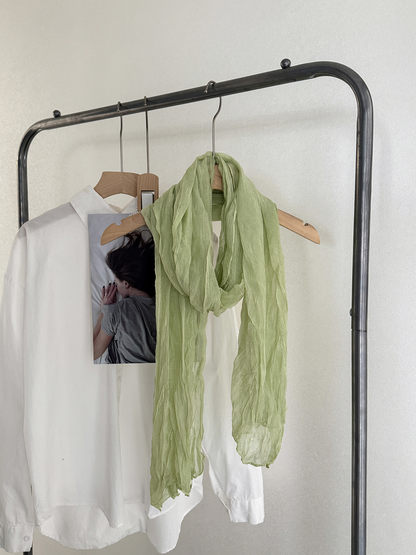 Green crinkled scarf draped on a hanger