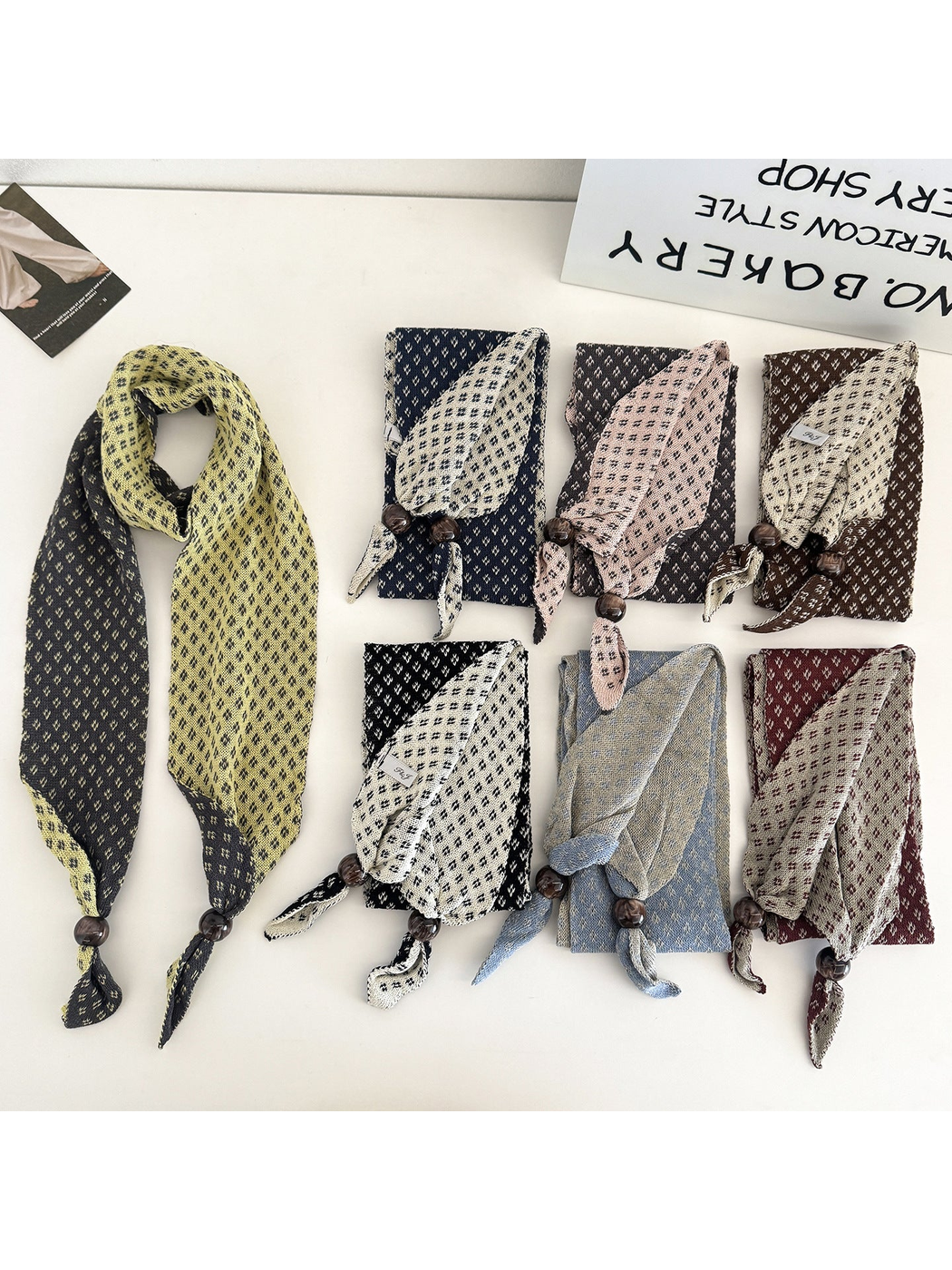 Seven color variations of the geometric-patterned narrow scarf displayed together