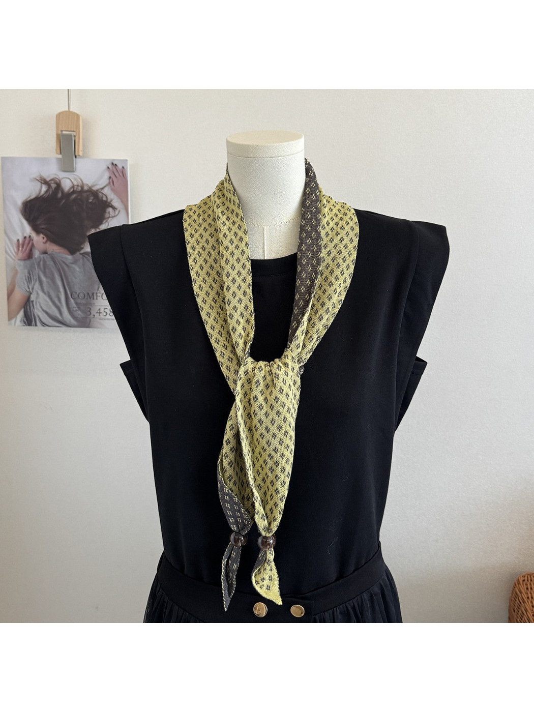 Yellow geometric-patterned scarf styled in a long front knot on a mannequin