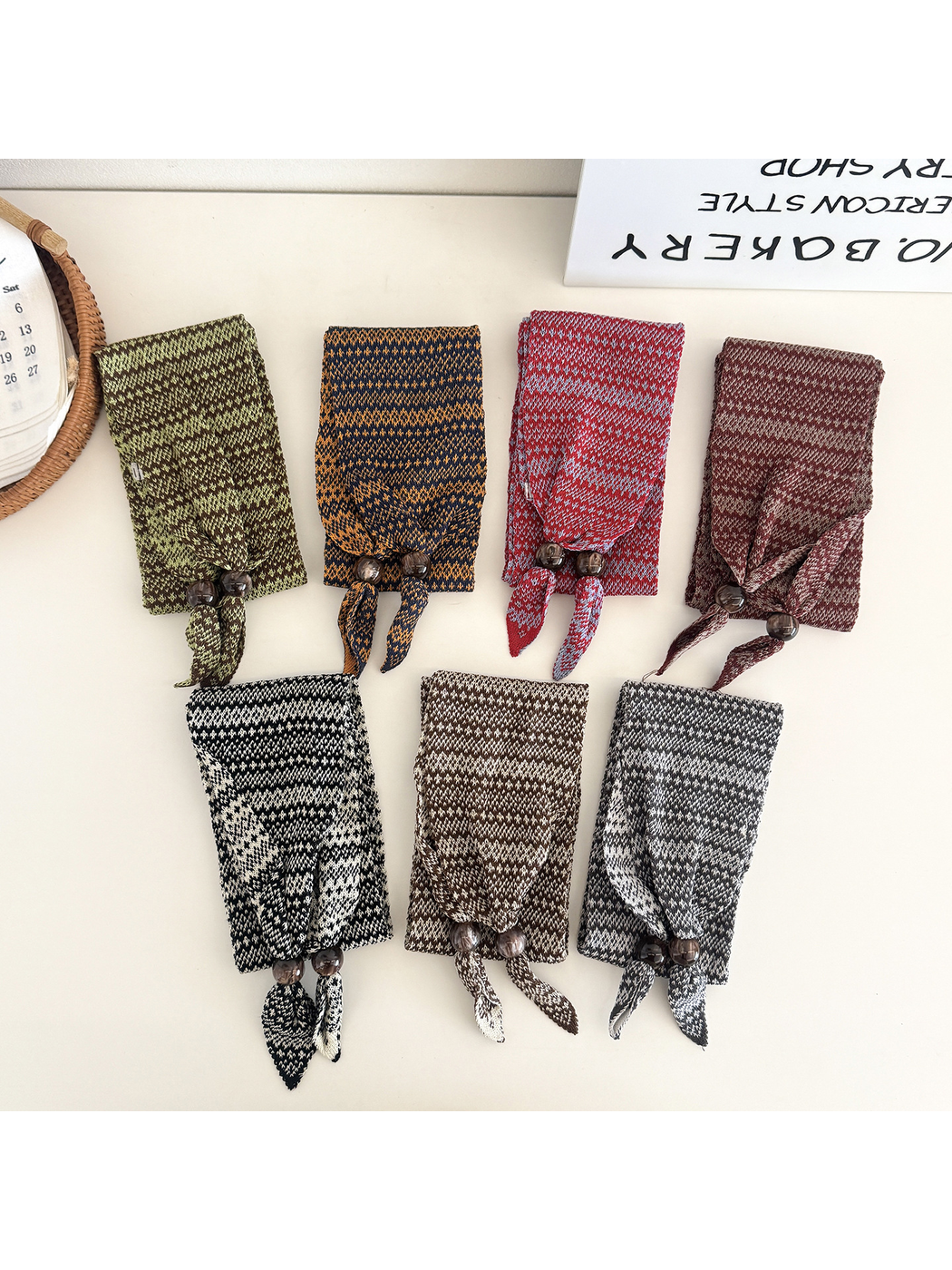 Seven colors of the geometric-pattern narrow scarf arranged in folded flat displays