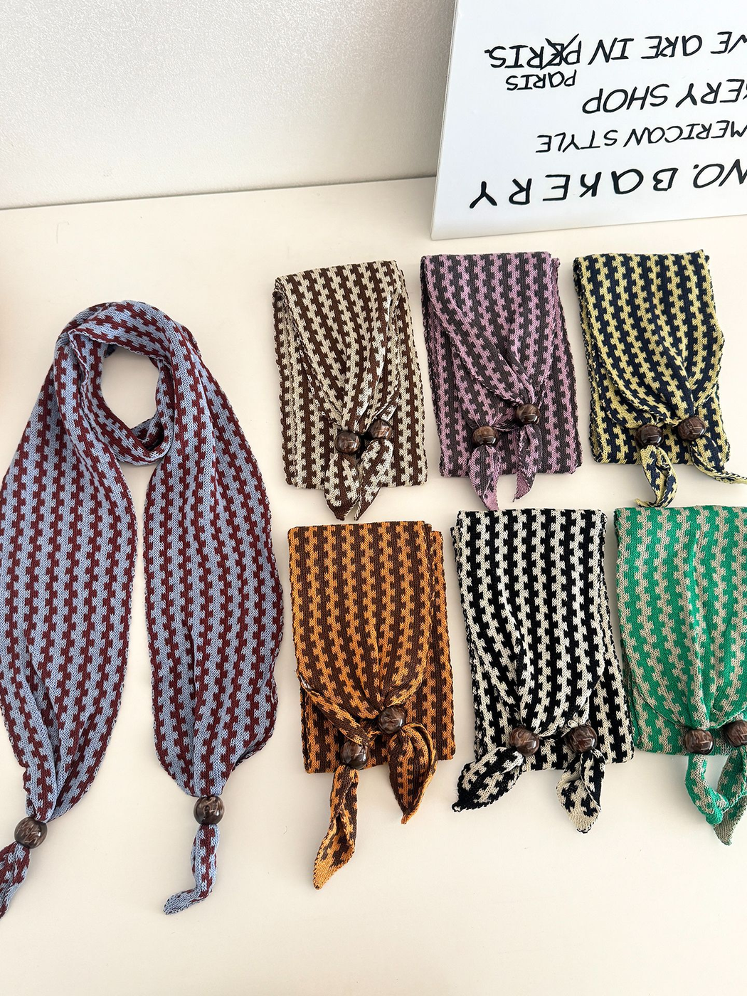 Seven color variants of the narrow patterned scarf arranged open and folded
