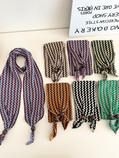 Seven color variants of the narrow patterned scarf arranged open and folded