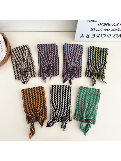 Seven folded color variants of the narrow patterned scarf with beaded ends