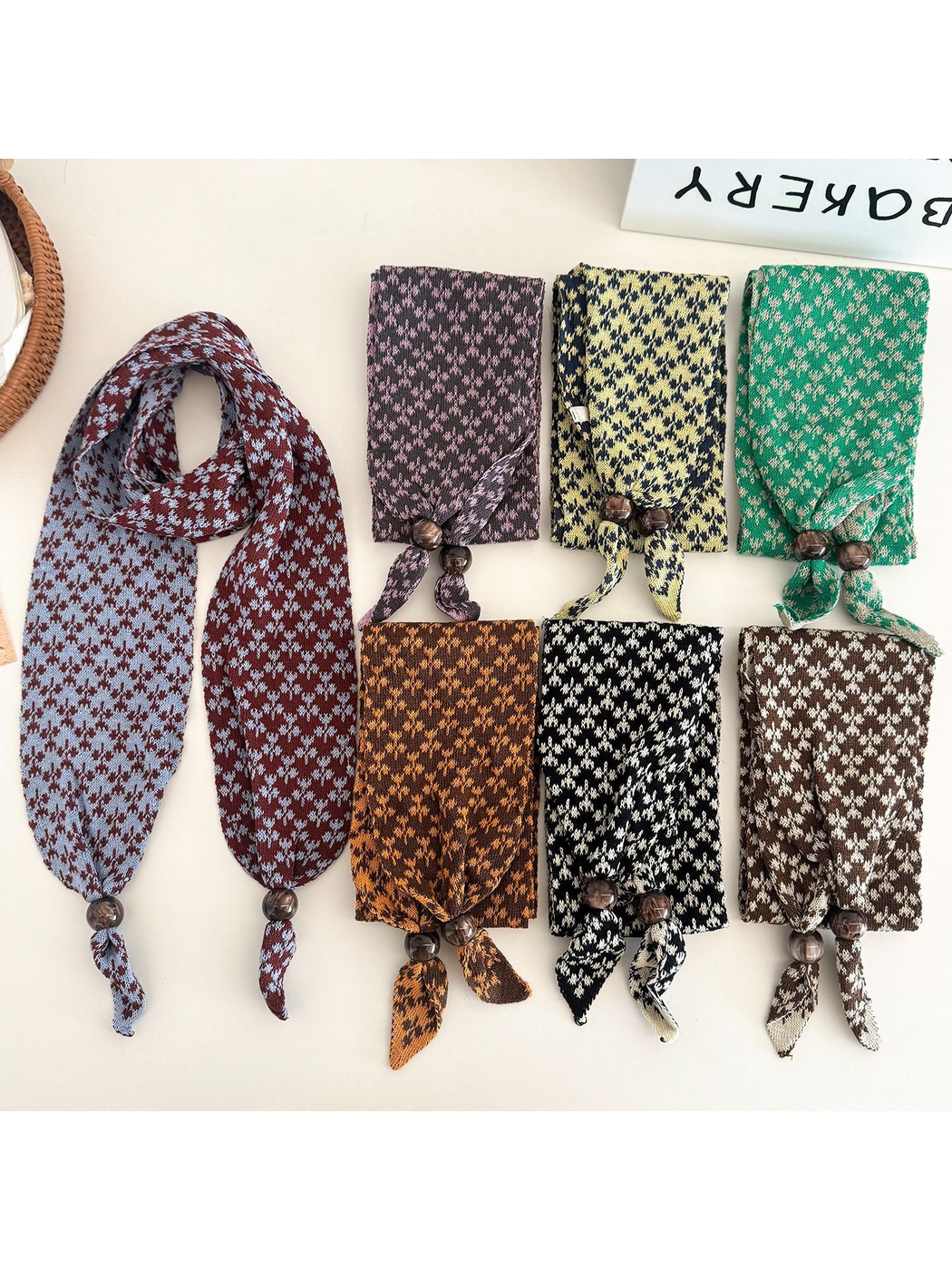 Seven patterned narrow scarves displayed in assorted colors