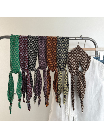 Assorted patterned narrow scarves draped over a clothing rack