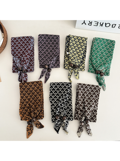 Seven patterned narrow scarves arranged by color