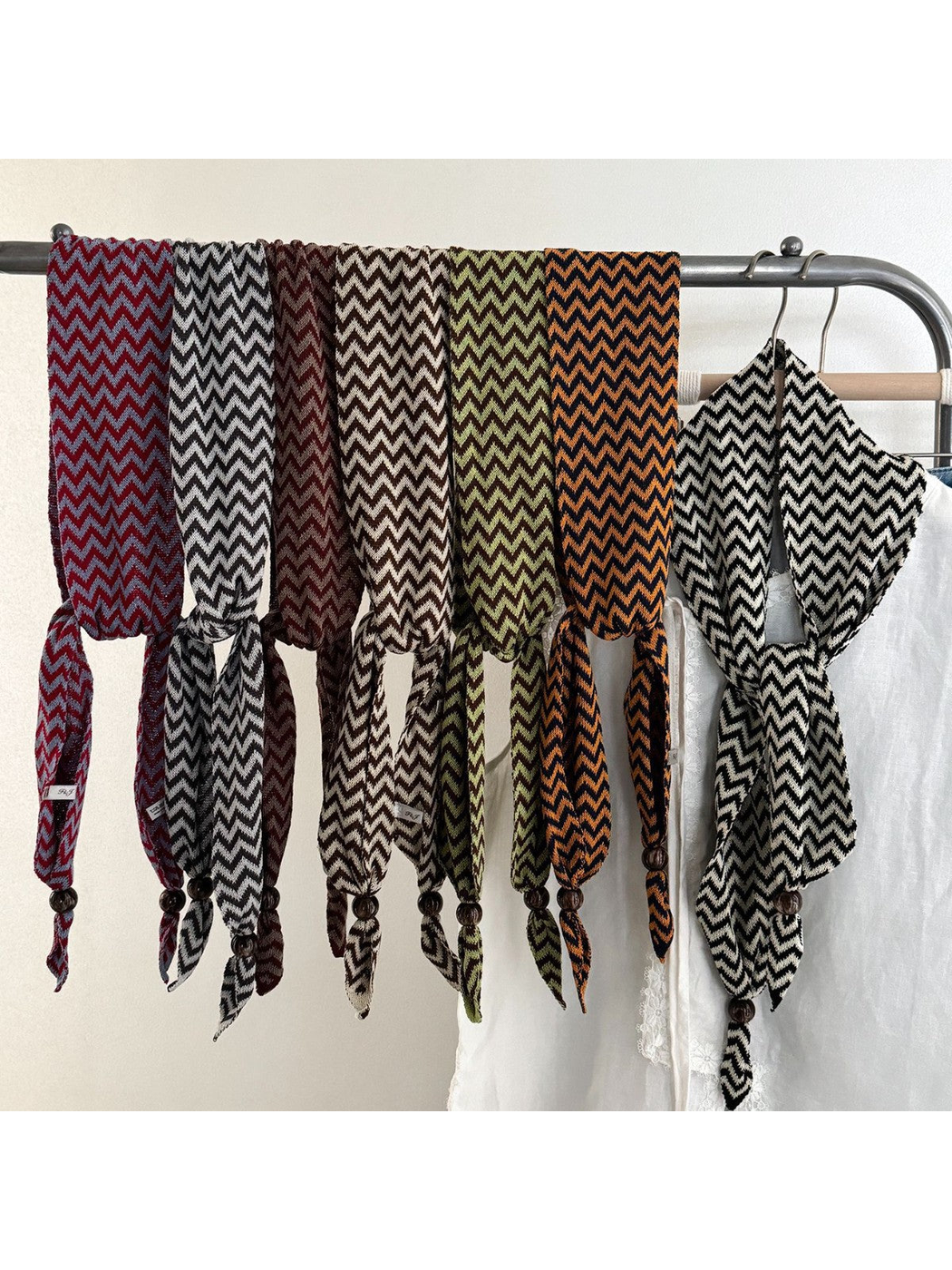 Seven zigzag scarf colors draped together on a clothing rack