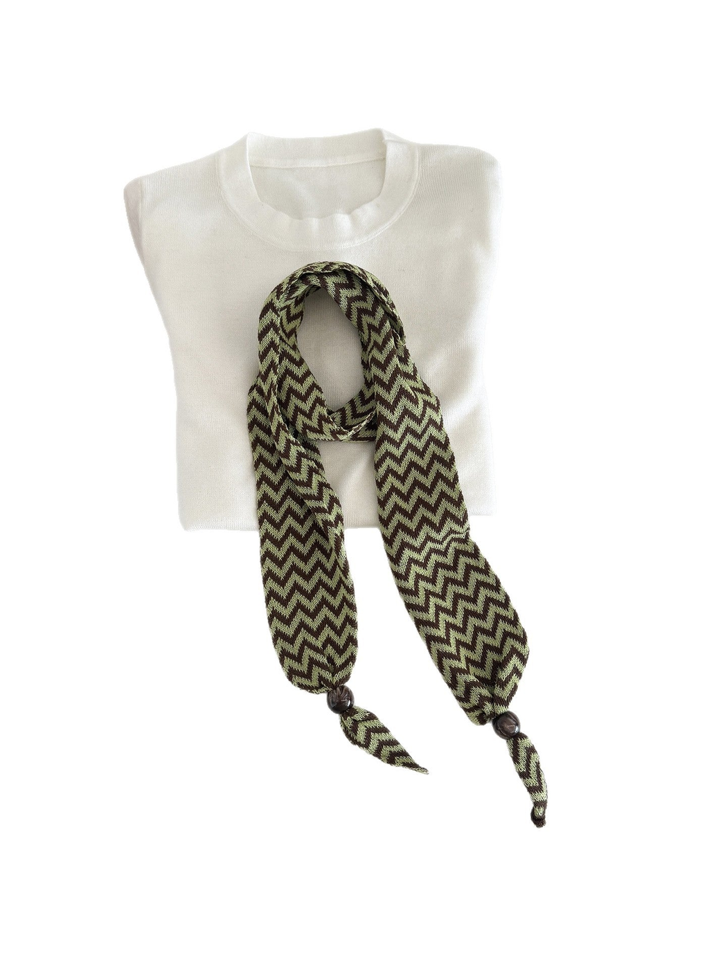 Green zigzag scarf arranged over a folded white top with bead-accented ends