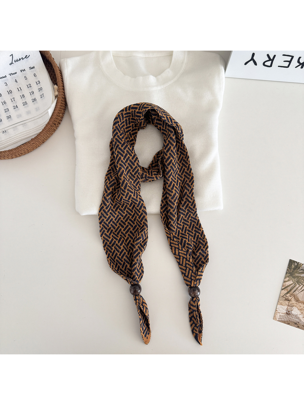 Orange geometric narrow scarf with beaded pointed ends, flat lay