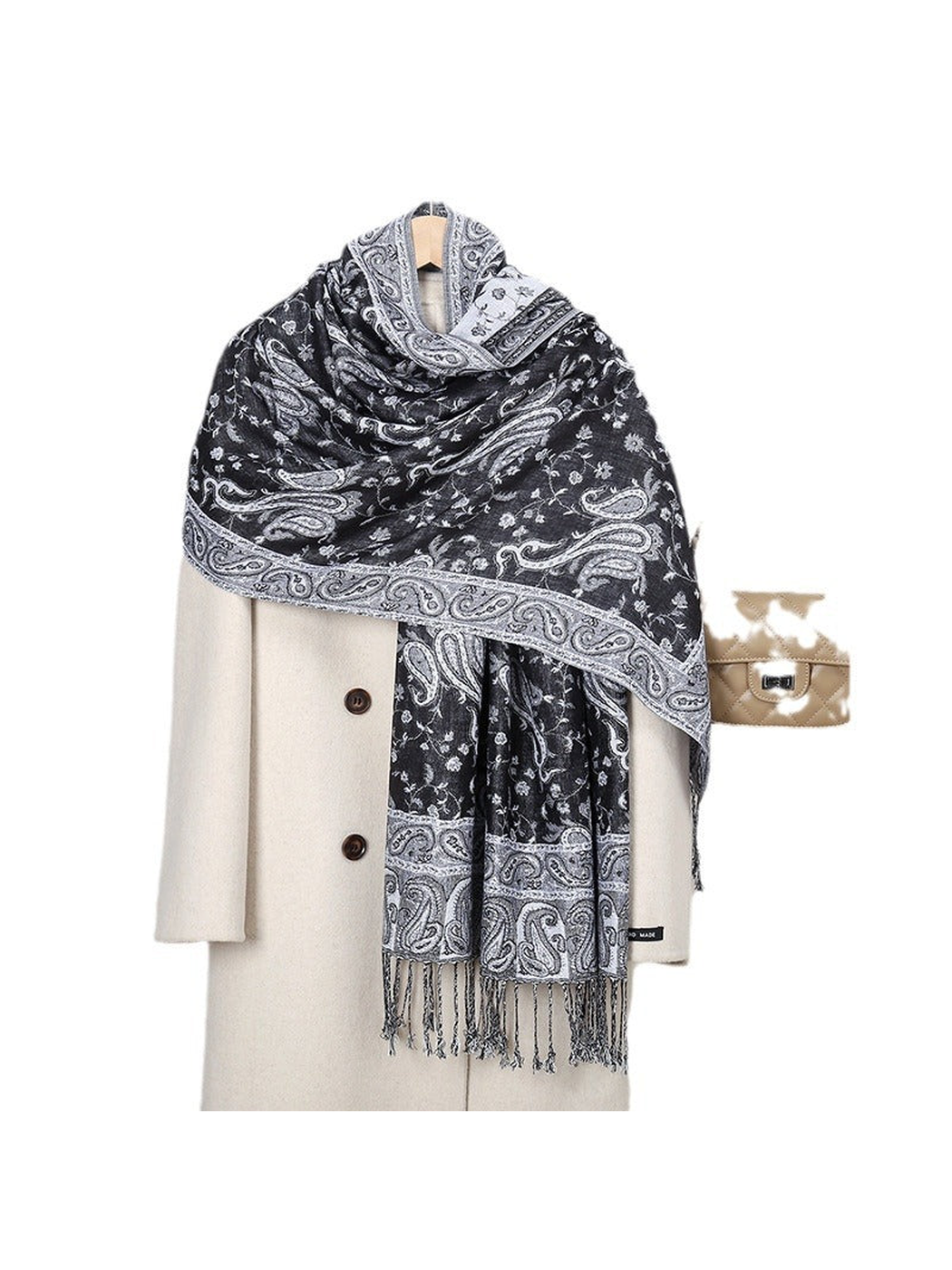 Black and gray paisley scarf with fringed ends draped over a cream coat