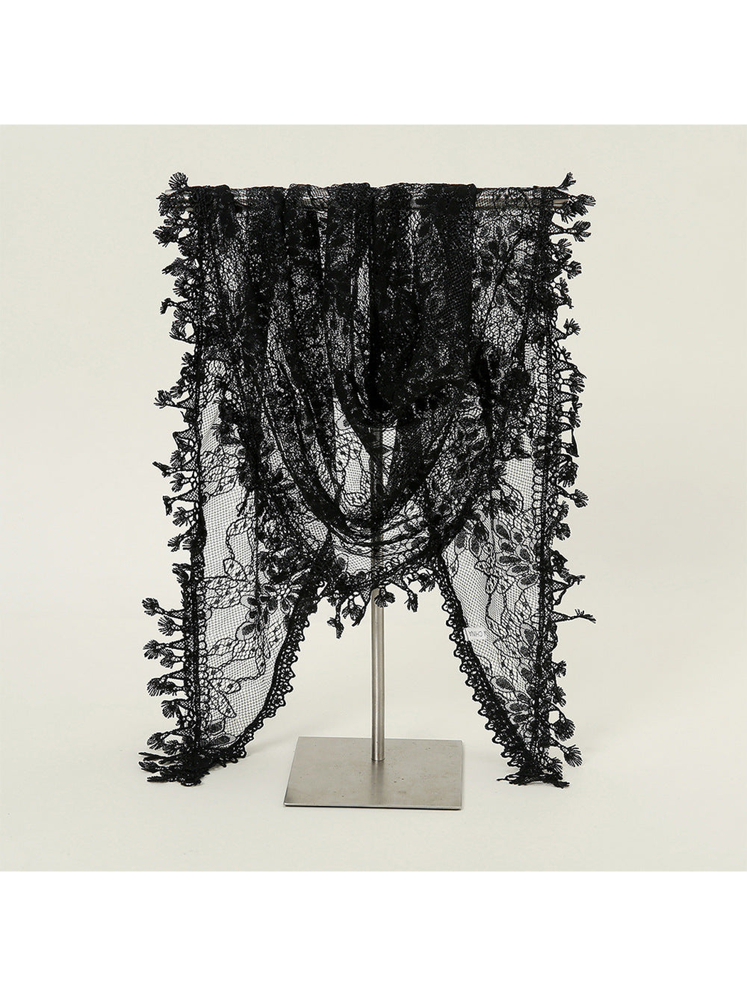 Black floral lace triangle scarf draped over a display stand