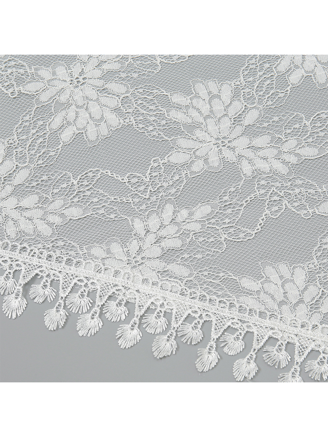 Close-up of white floral lace mesh and decorative fringe edging