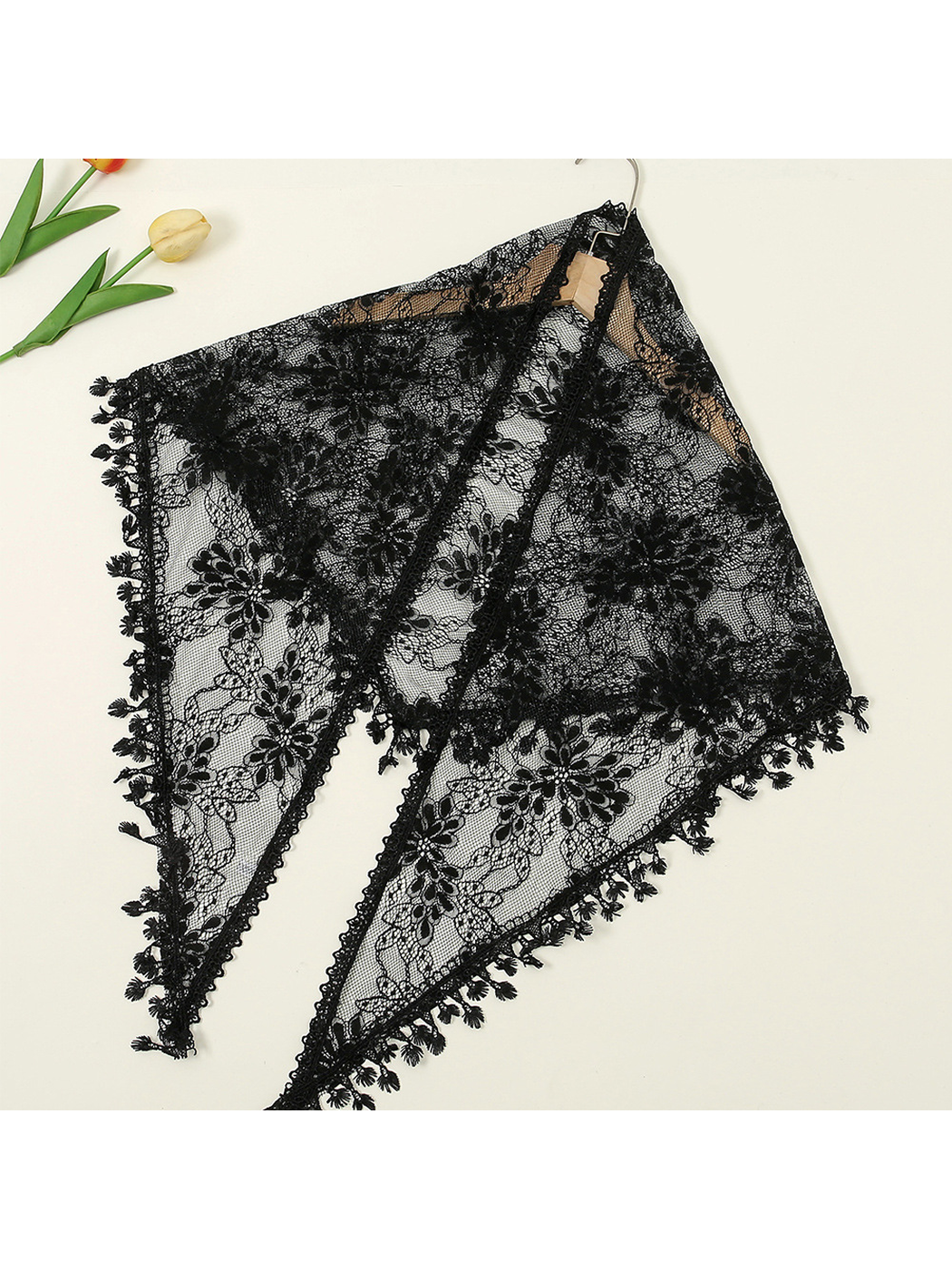 Black floral lace triangle scarf displayed flat on a hanger
