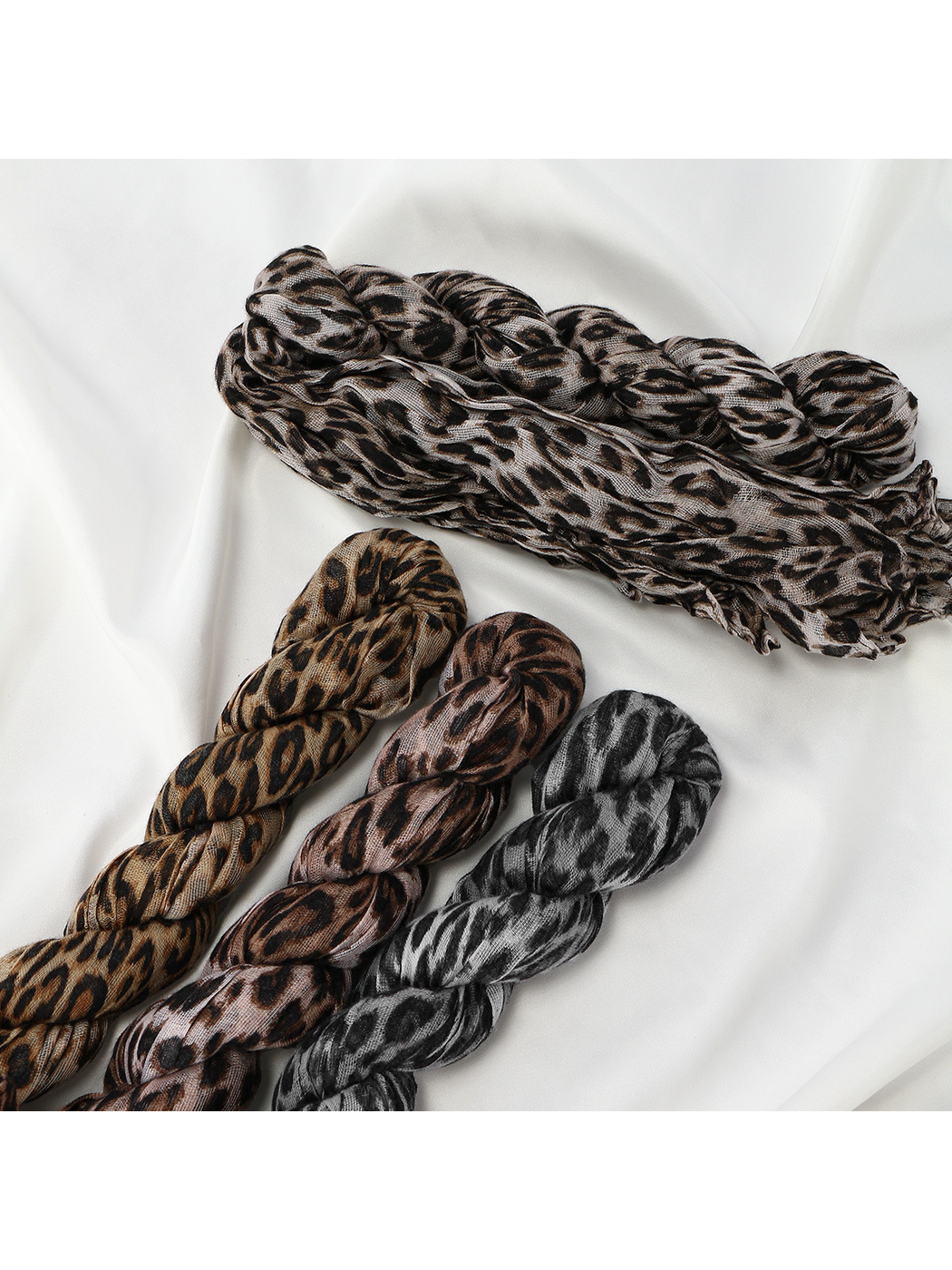 Close-up of braided crinkled leopard-print scarves in four colorways