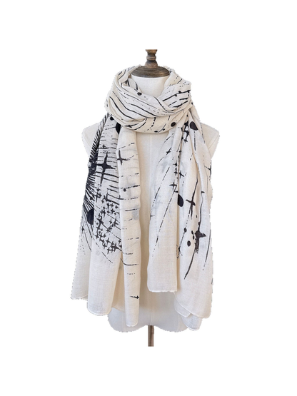 Ivory-toned scarf with black abstract line and dot pattern wrapped and draped on a display form