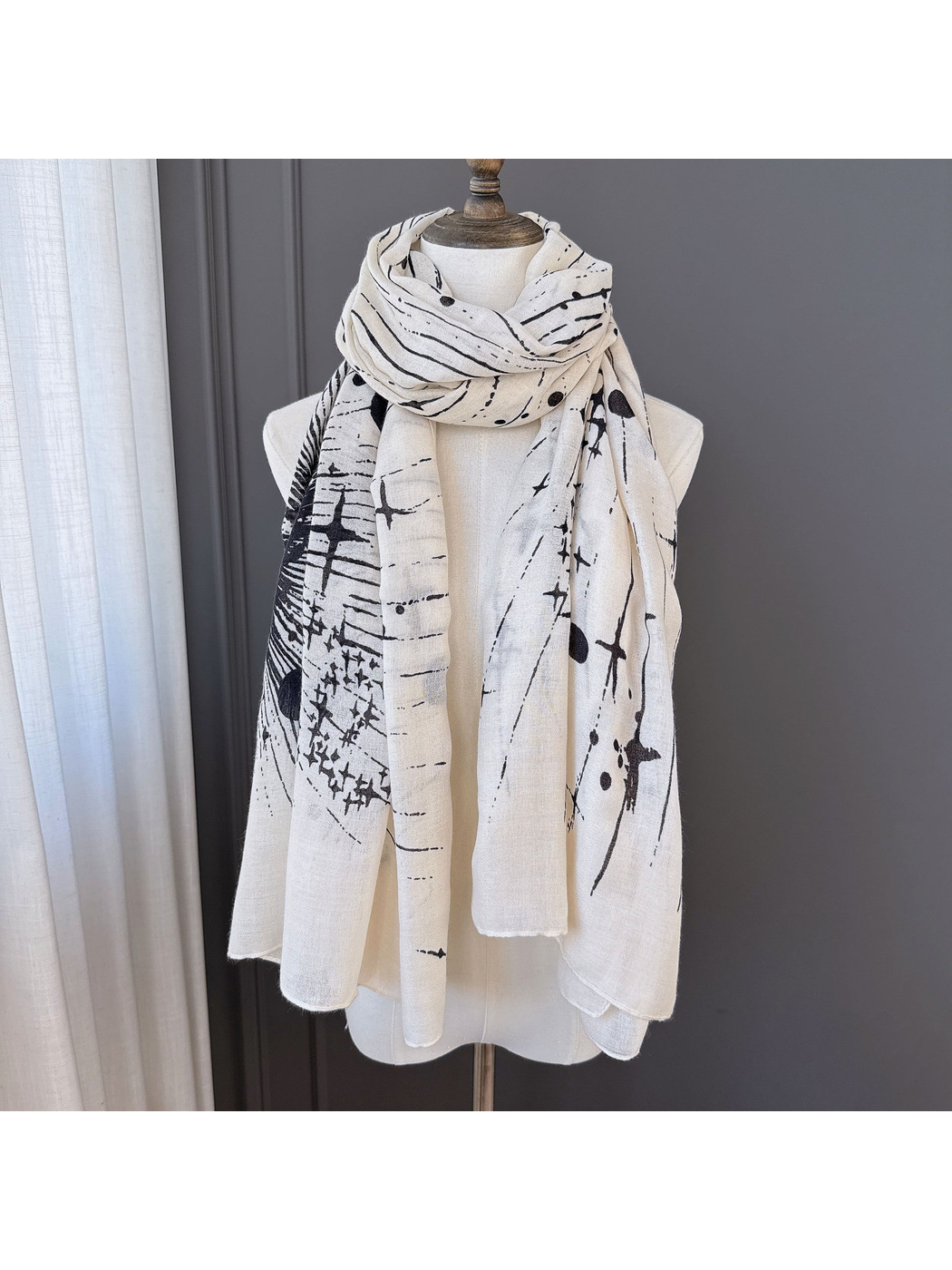 Ivory-toned scarf with black abstract pattern wrapped and draped on a display form