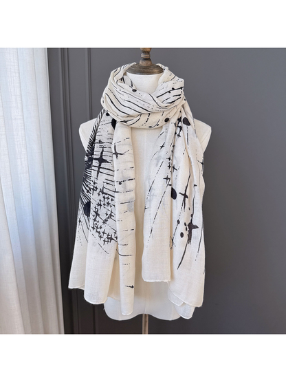Ivory-toned scarf with black abstract pattern wrapped and draped on a display form