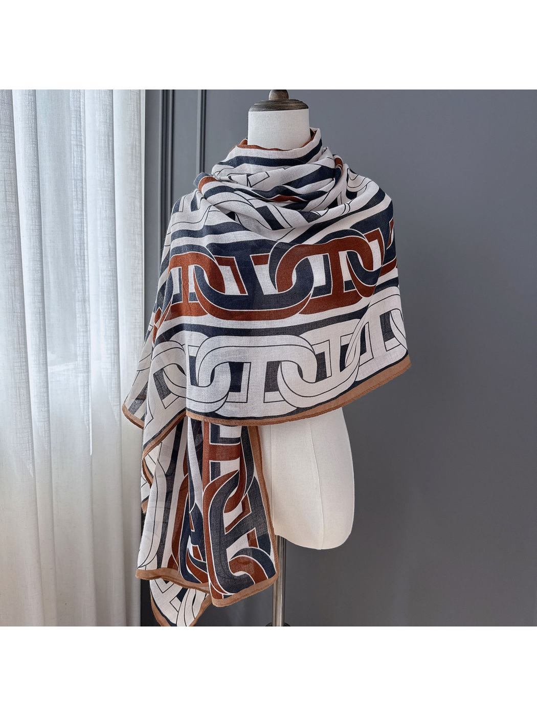 Multicolor geometric scarf wrapped across a dress form as a shawl