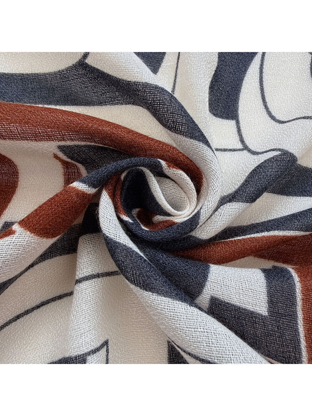 Close-up of the scarf's open woven-look texture and navy, rust and ivory pattern