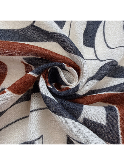 Close-up of the scarf's open woven-look texture and navy, rust and ivory pattern