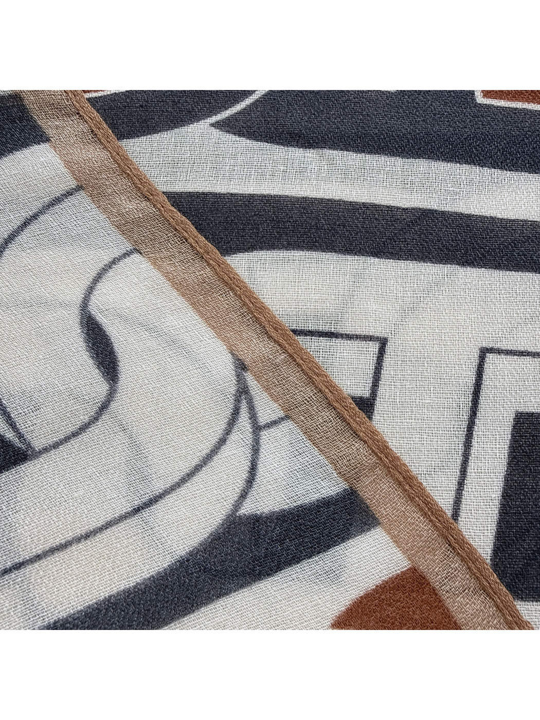 Close-up of the camel-brown bound edge and geometric scarf pattern