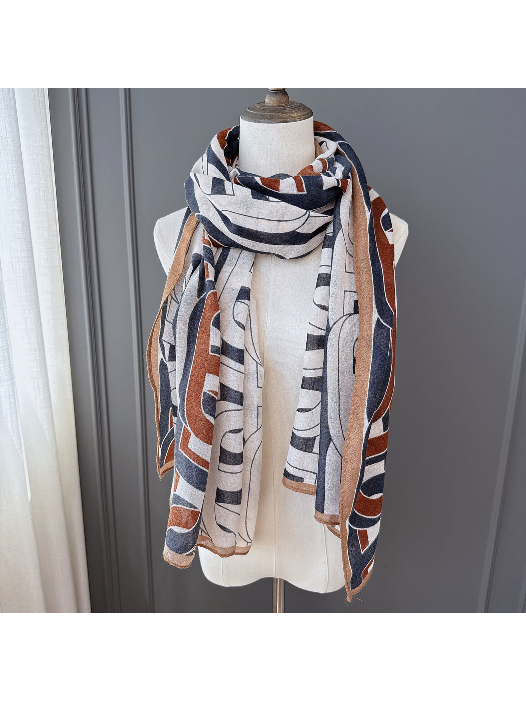 Multicolor geometric scarf looped around a dress form with long ends hanging