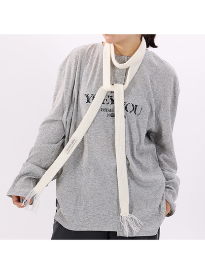 Ivory narrow knit scarf styled over a gray top