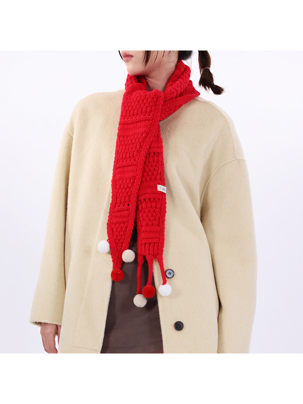 Red tapered scarf styled around the neck with pom-pom-tipped ties