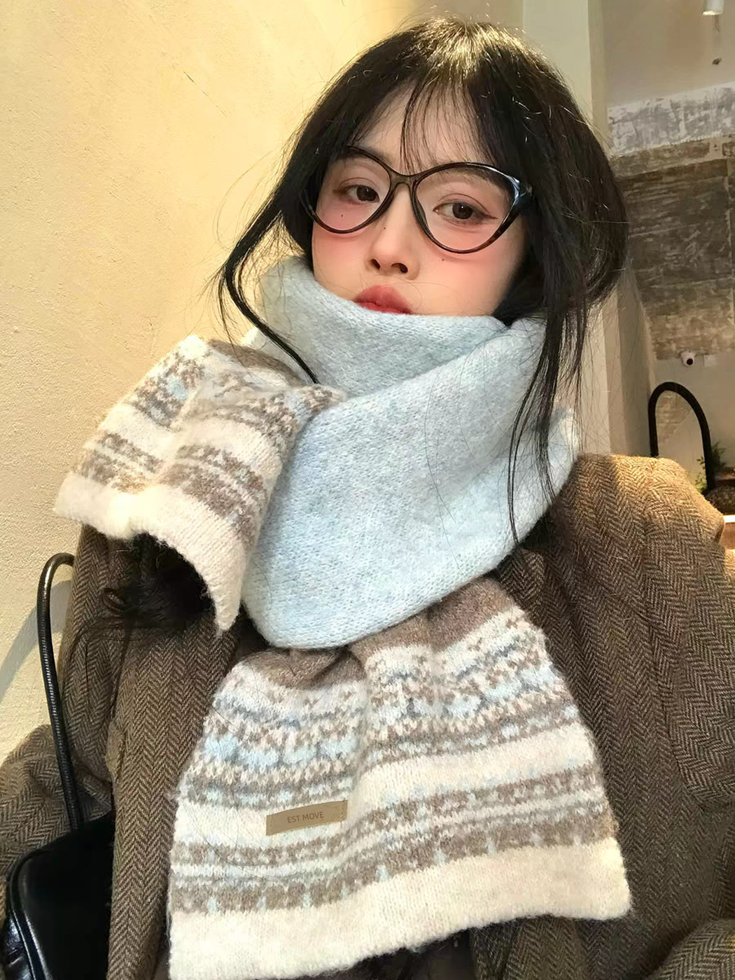 Blue geometric-pattern scarf worn indoors with a brown coat