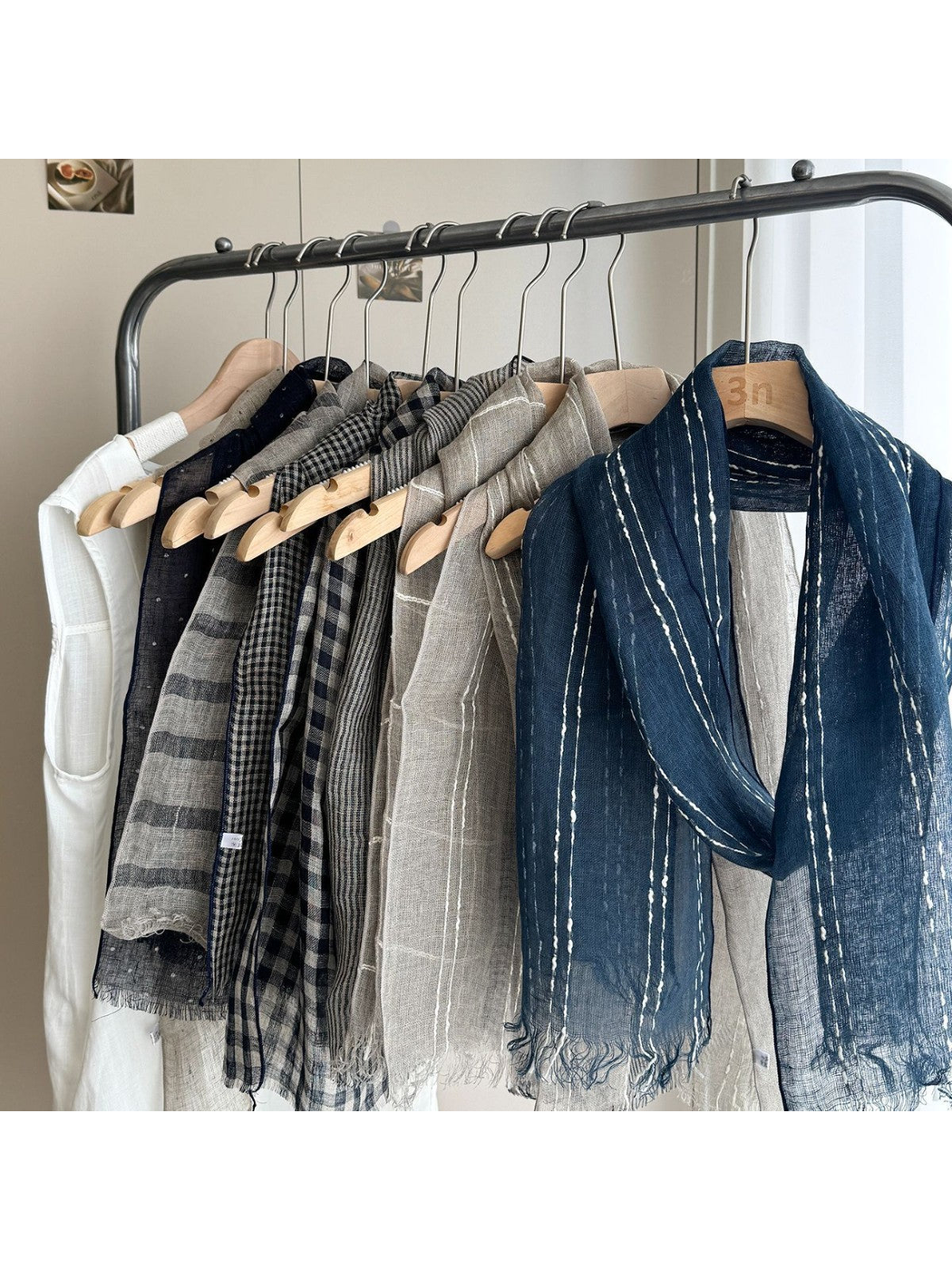 Multiple patterned scarf styles displayed together on a clothing rack