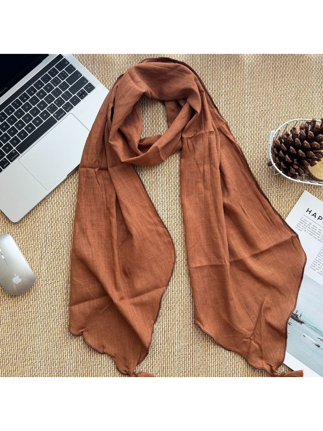Orange tassel scarf arranged flat beside desk accessories