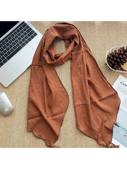 Orange tassel scarf arranged flat beside desk accessories