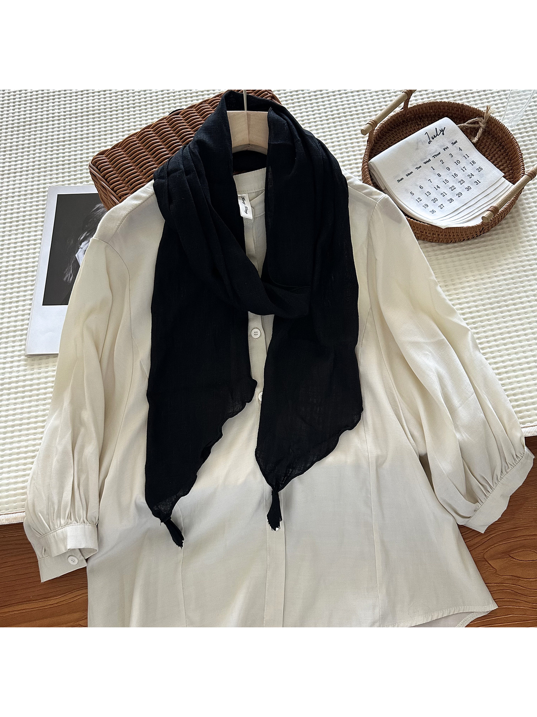 Black tassel scarf styled over an ivory blouse