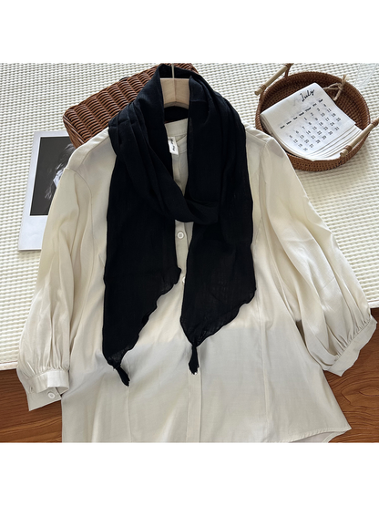 Black tassel scarf styled over an ivory blouse