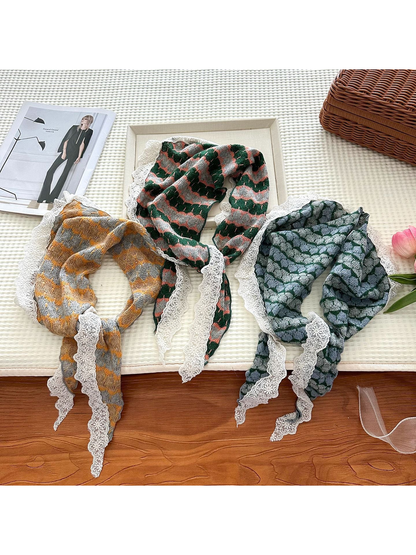 Three striped triangle scarves with white lace edging arranged on a tabletop