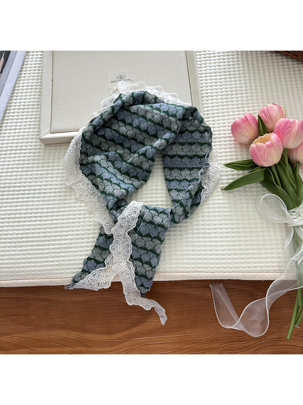 Blue and green striped triangle scarf styled beside pink flowers