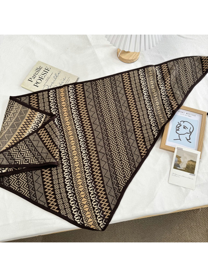 Multicolor geometric triangle scarf laid flat with dark brown trim and tie ends