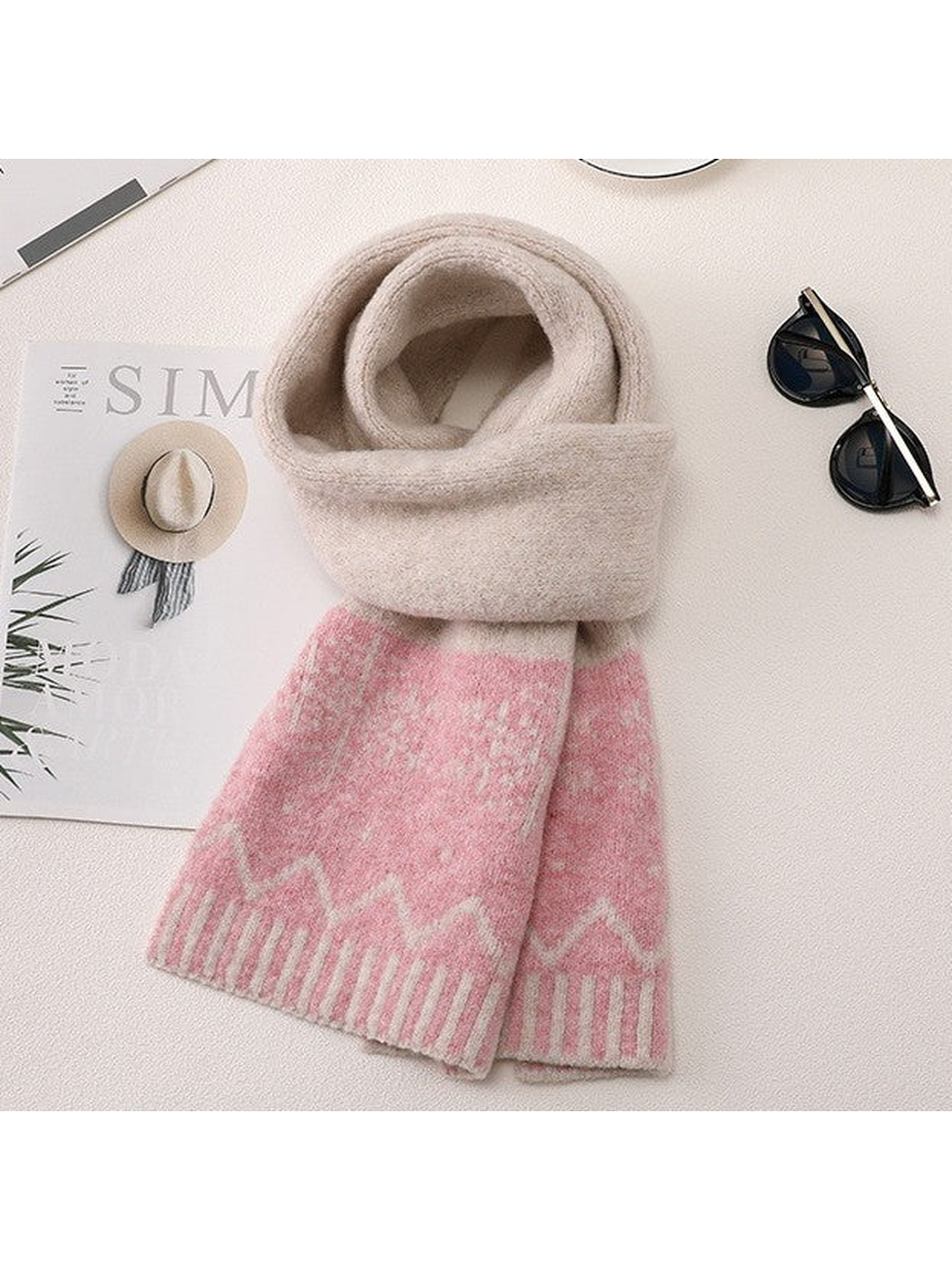 Beige long scarf with pink snowflake motifs arranged with sunglasses